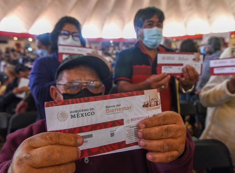 Beneficiarios recibiendo apoyos de la Pensión del Bienestar. Adultos mayores posando con sus tarjetas del Bienestar.