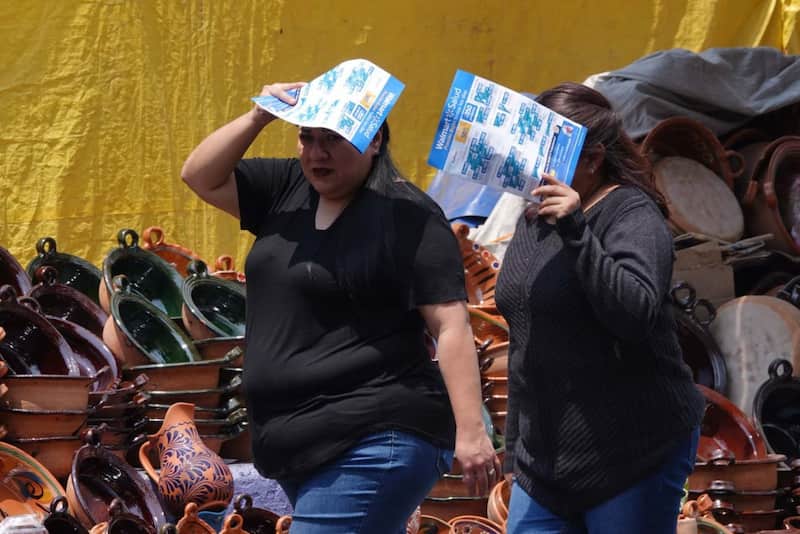 la secretaría de salud ha documentado muertes por calor dos personas se cubren del sol mientras caminan en las calles de la cdmx