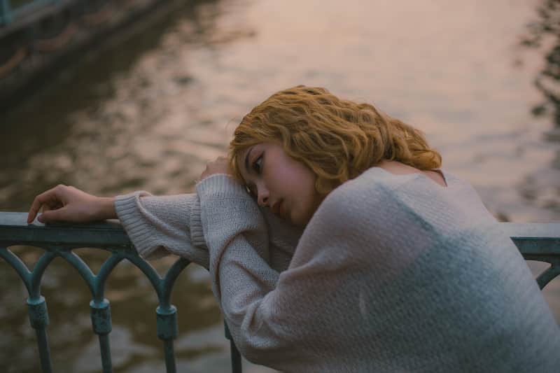 el síndrome puede causarse por estrés emocional muy fuerte una chica triste recargada en un barandal